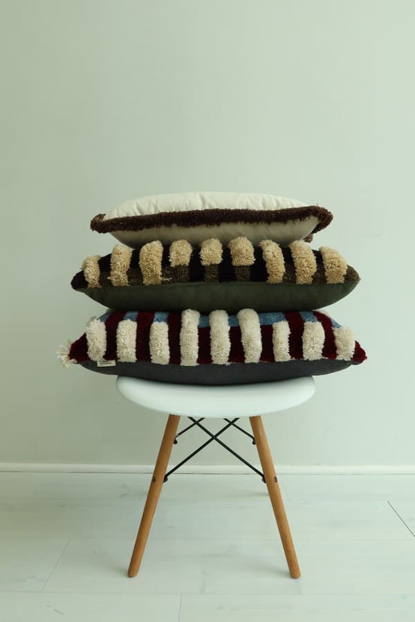 Four scatter cushions from the collection stacked on a chair