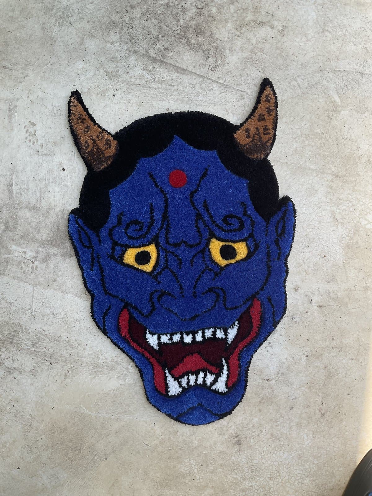 Hand-tufted rug of a blue oni demon mask with red horns