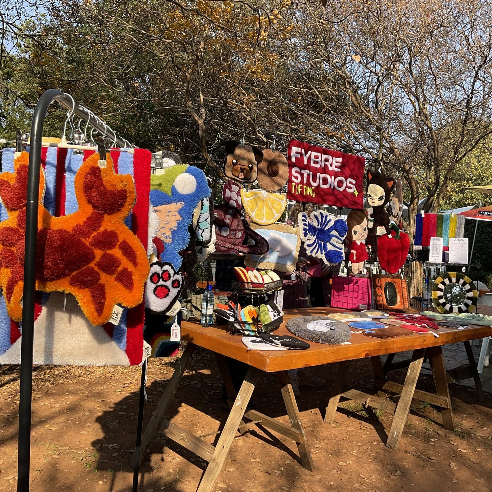 Tufted rugs and patches displayed on an outdoor market table